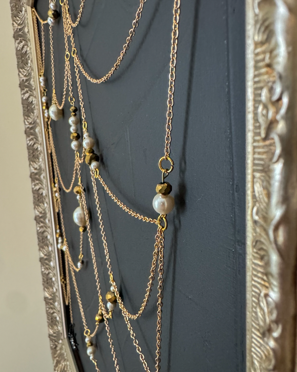 Side detail of Weaver showing dimensional gold chain and pearls above textured black canvas