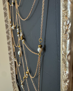 Side detail of Weaver showing dimensional gold chain and pearls above textured black canvas