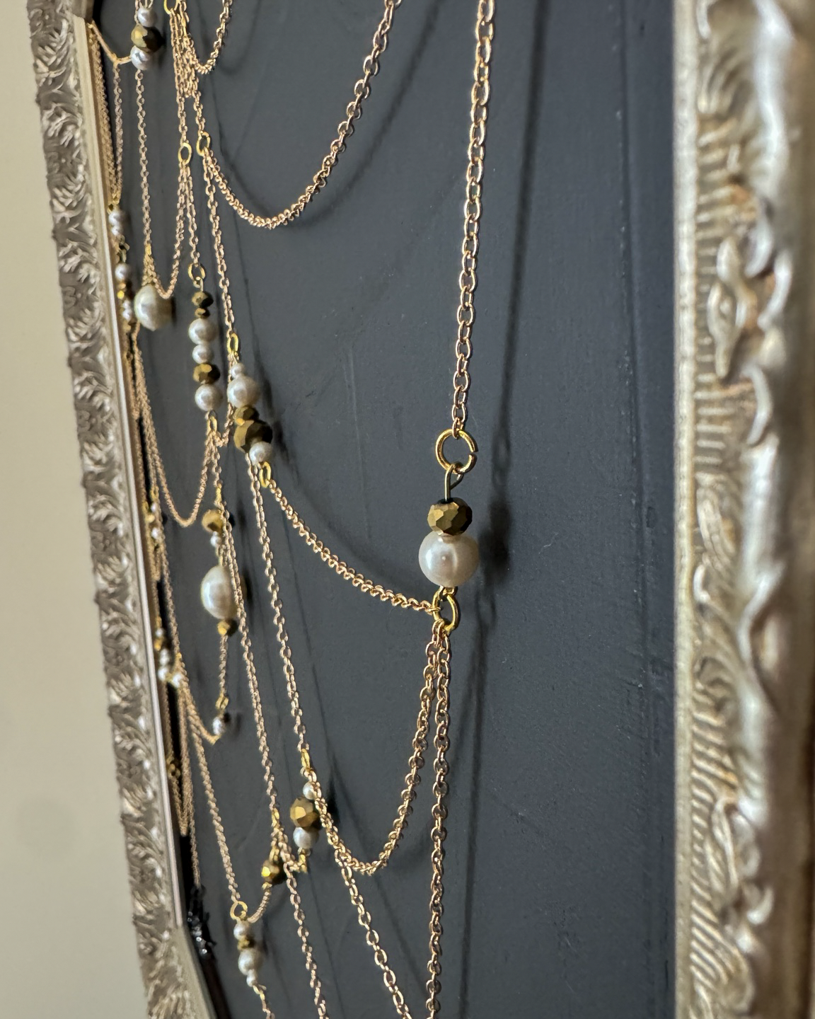 Side detail of Weaver showing dimensional gold chain and pearls above textured black canvas