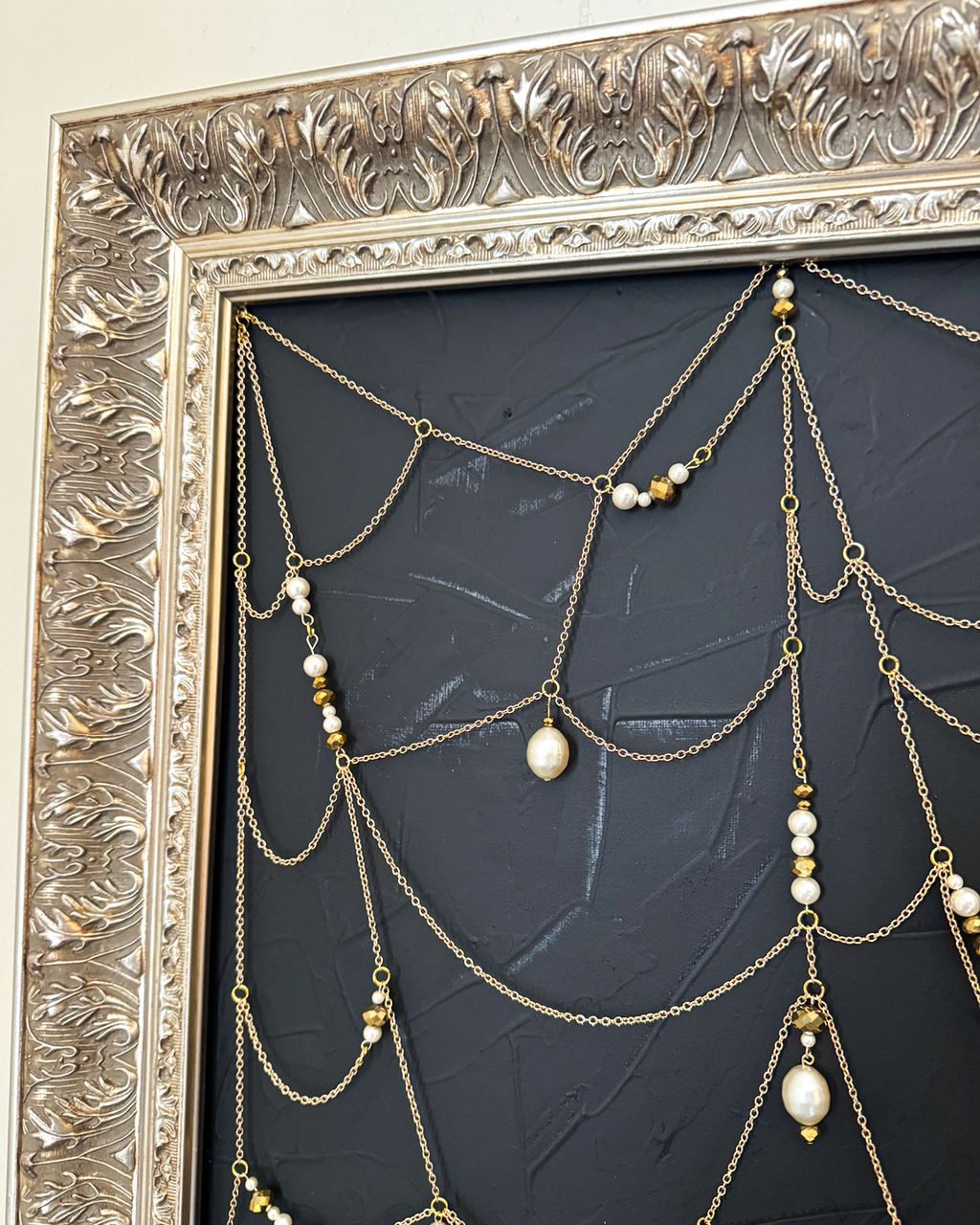 Close detail of Weaver gold chain web, pearls, beads, and ornate frame