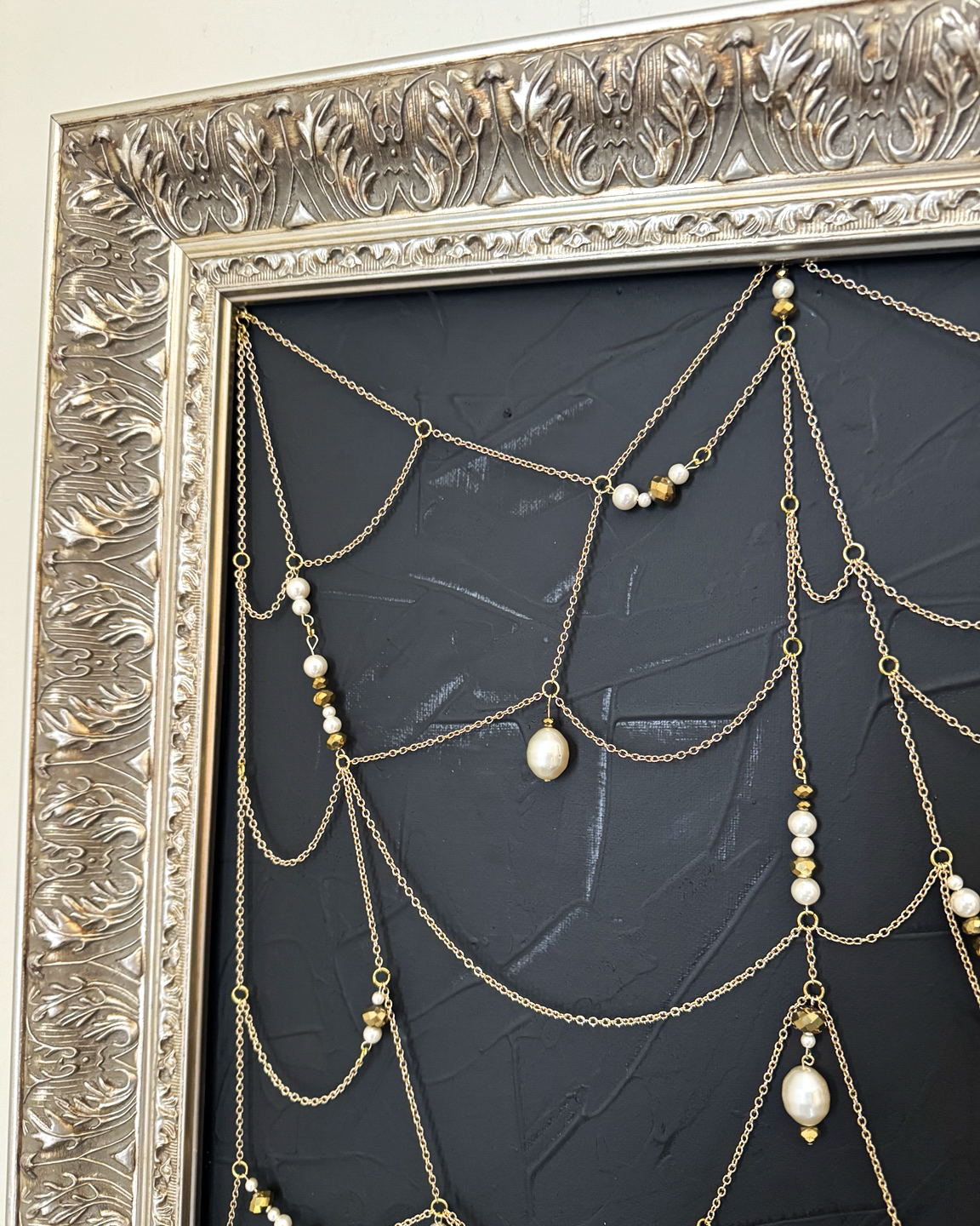 Close detail of Weaver gold chain web, pearls, beads, and ornate frame